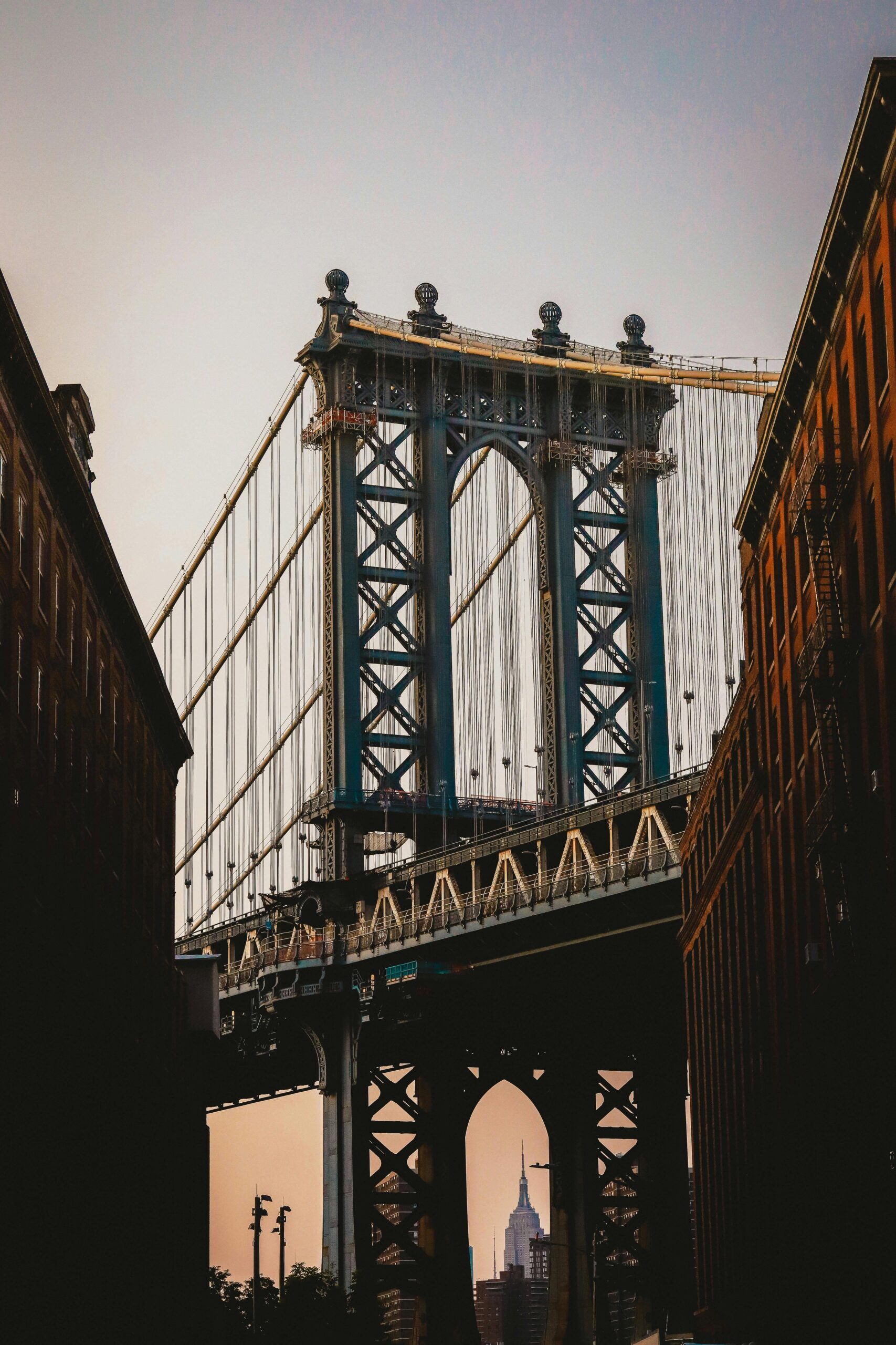 A stunning view of the Brooklyn Bridge at dusk with the Empire State Building in the background.
