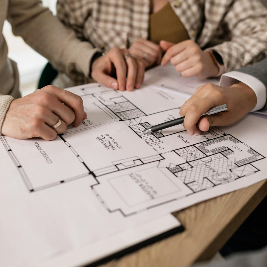 People discuss architectural plans in a real estate planning session, highlighting teamwork.